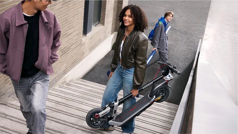 Femme portant la trottinette pliée Segway Ninebot E3 E dans un escalier