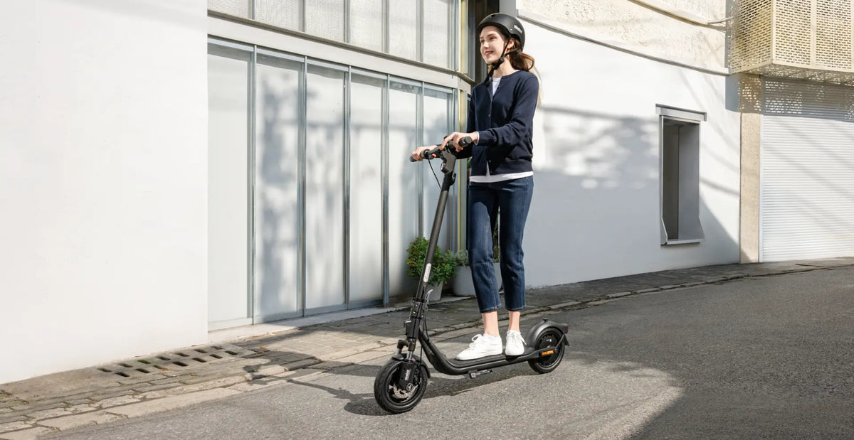 Femme conduisant la trottinette électrique Segway Ninebot F2 E II en ville