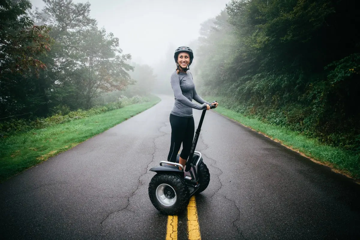 Femme sur le gyropode tout-terrain Segway i2 XE sur une route brumeuse