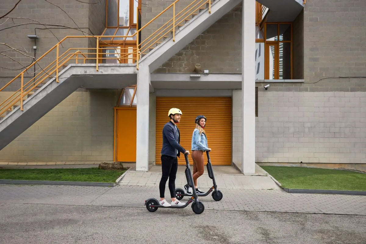 Deux personnes avec casques Segway Ninebot et trottinettes électriques en ville