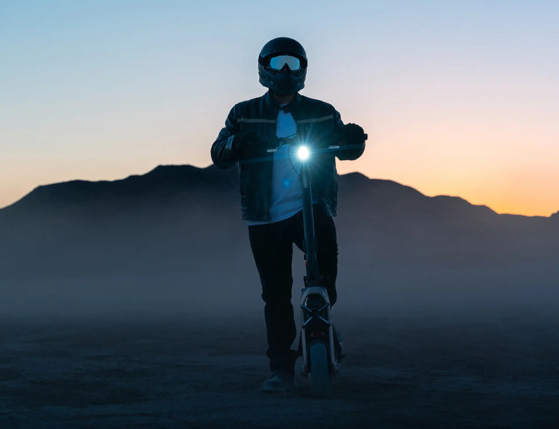 Conducteur sur la trottinette électrique Segway GT3 E au crépuscule, phare allumé